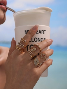 Macro detail of gold stackable rings with 5A zircon hearts and pearls on female hand