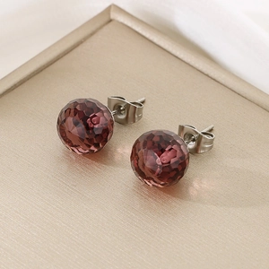 Macro shot of dark purple faceted crystal earrings on a champagne metal display tray