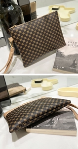 Detail of vintage brown clutch purse with gold clover pattern and leather wristlet