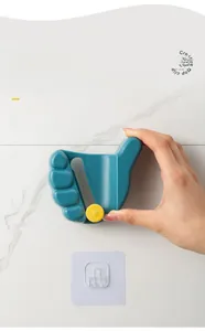 Close-up of wall-mounted thumb-shaped mop holder with adhesive pad installation