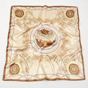 Detailed pattern of beige silk scarf with baroque chains and central medusa emblem