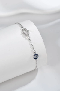 Detail of silver Hamsa Hand and Evil Eye bracelet with blue zircon inlay on white stand