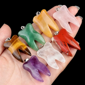 Set of seven natural crystal tooth pendants held in hand with various gemstones