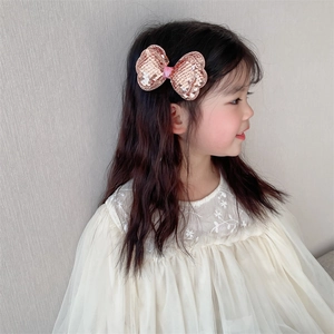 Detail view of pink sequin bow hair clip worn by a young girl for party hairstyles