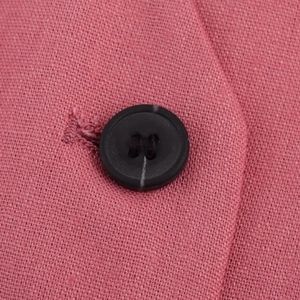 Detail of pink linen blend fabric with a high-quality black button and woven texture