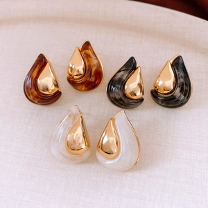 Close-up of teardrop resin earrings in amber, black, and white with 18K gold plating