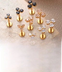 Detailed view of titanium flower labret studs with zircon in black, gold and clear crystals