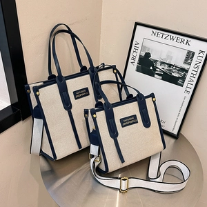 Contrast canvas tote bag with navy blue leather trim and striped shoulder strap
