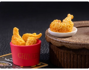 Vue macro de pilons de poulet frits miniatures dans un seau rouge et une petite assiette