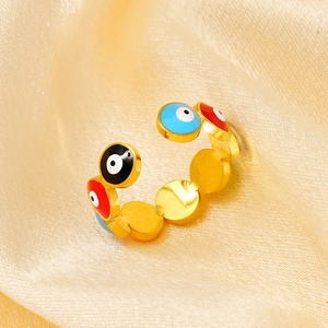 Macro shot of gold plated evil eye rings with blue and red enamel details on silk fabric