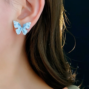 Gros plan de boucles d'oreilles papillon avec zircon bleu porté par un mannequin