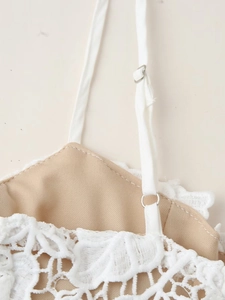 Détail des bretelles réglables de la robe en dentelle blanche avec boucles métalliques