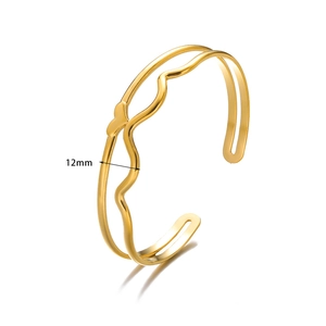 Detail of 12mm wide gold wave pattern open cuff bracelet with small heart accent
