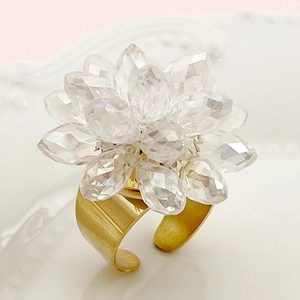 Elegant gold-tone ring with crystal flower bead design on a decorative background
