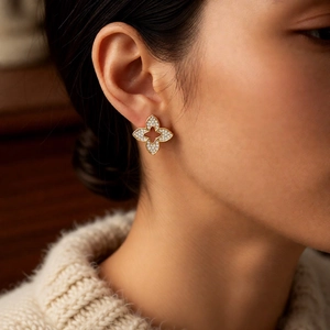 Detail shot of gold-plated flower stud earrings with zircon inlay on model's ear