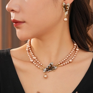 Close-up of vintage butterfly pearl necklace and earrings set worn by a model