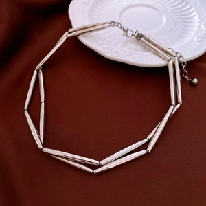 Close-up of geometric silver metal necklace with tubular links on a red velvet background