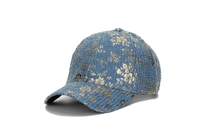 Dettaglio del berretto da baseball in tweed blu con stampa floreale oro e trama tessuta