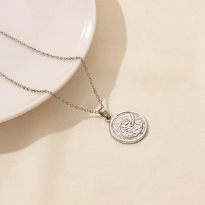 Detail shot of vintage silver starfish coin pendant with fine link chain on elegant ceramic