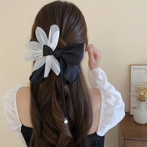 Detail of white organza flower and black ribbon hairpin with pearl pendant on hair