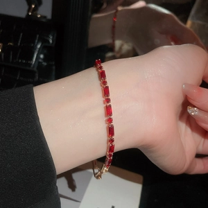 Detailed macro view of 18k gold ruby tennis bracelet with emerald-cut stones on a wrist