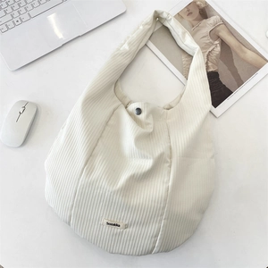 Détail d'un sac cabas en velours côtelé blanc cassé avec bouton pression et logo