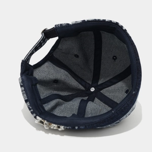 Detail of blue denim miki hat showing inner stitching, metal buckle, and frayed edges