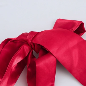 Nœud en satin rouge élégant sur une robe bouffante avec une texture lisse et brillante