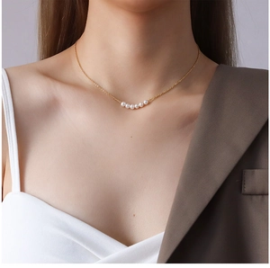 Close-up of 18K gold-plated choker with a horizontal row of five pearls on a model