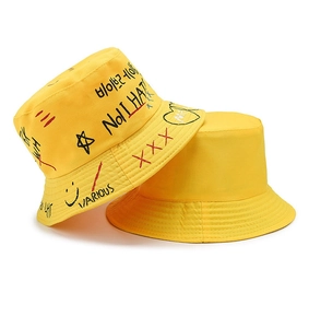 Detail of yellow cotton bucket hats featuring hand-drawn graffiti and solid minimalist style