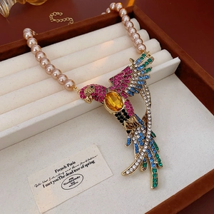 Detailed top view of a pearl and rhinestone parrot pendant in a luxury jewelry box