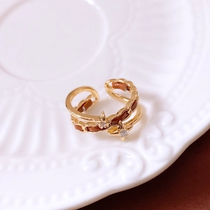 Detailed shot of gold-plated star ring with brown enamel and zircon on ceramic tray