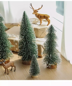 Close-up of snowy miniature Christmas trees and reindeer figures with wooden bases
