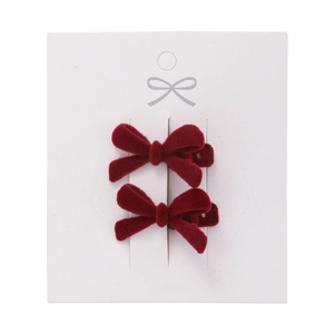 Pair of festive red velvet bow hair clips for women on a white display card