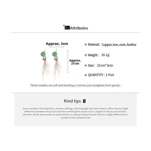 Détail des boucles d'oreilles à plumes avec dimensions 21cm par 3cm et perles en résine