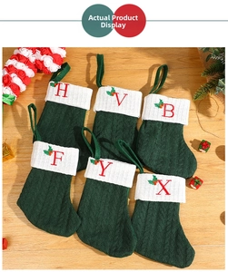 Detail of green knit Christmas stockings with white faux fur cuff and red letter embroidery