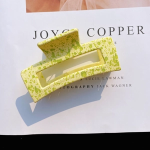 Detail of a large matte rectangular hair claw clip with yellow and green marble texture