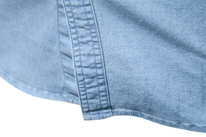 Close-up of light blue denim shirt hem showing high-quality stitching and fabric texture
