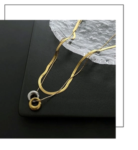 Close-up of gold double-layer snake chain necklace with interlocking gold and silver rings