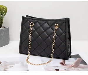 Detail of black quilted PU leather tote with gold chain strap and metallic hardware