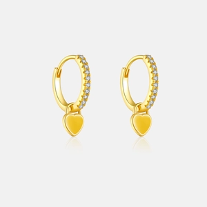 Détail de boucles d'oreilles créoles dorées avec zircons blancs et pendentifs cœurs