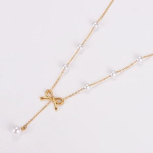 Detailed view of a gold bow pearl necklace with elegant white accents on white background