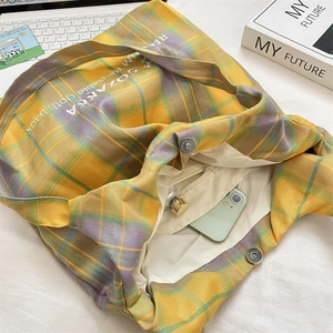 Detail of checkered canvas tote bag showing metal snap button and interior zipper pocket