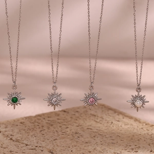 Detail showing four silver starburst necklaces with green, white, pink and pearl pendants