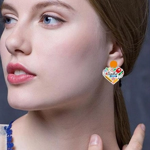 Détail de boucles d'oreilles cœur en acrylique pour enseignant avec motifs ABC et crayon