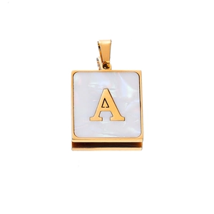 Macro detail of square gold pendant with white mother of pearl and letter A charm
