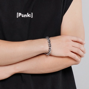 Détail d'un bracelet gourmette torsadé en acier inoxydable argenté poli porté au poignet