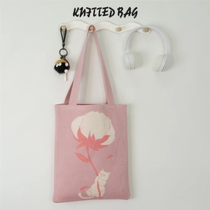 Close-up of pink knitted tote bag featuring white floral patterns and cat line art