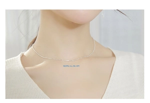 Close-up of minimalist S925 sterling silver barrel necklace worn on a female neck