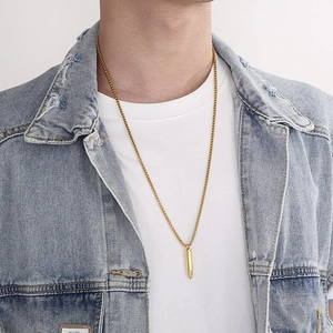 Collana da uomo con ciondolo a proiettile dorato e catena box indossata da un modello maschile